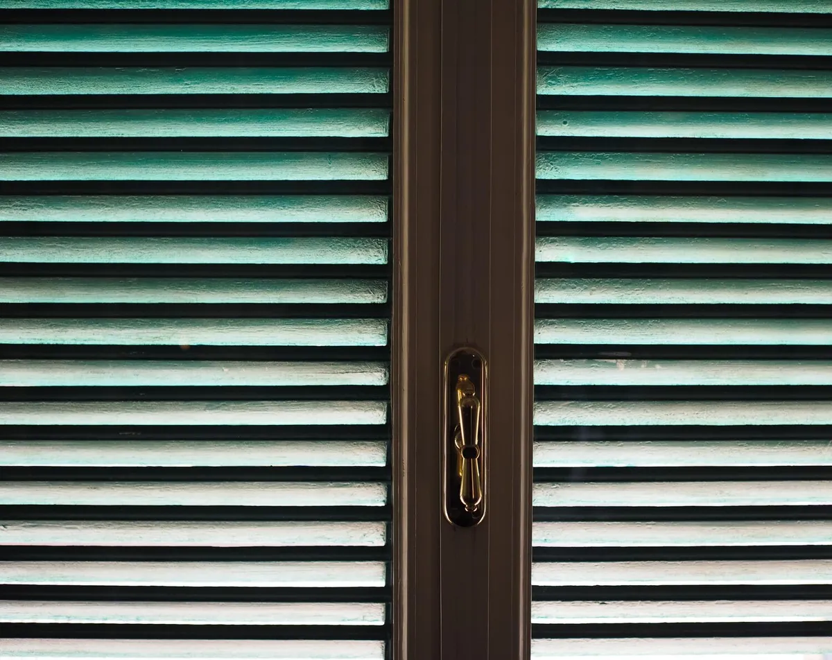 Lames d'un tablier de volet roulant fermé, vues de près depuis l'intérieur d'une fenêtre